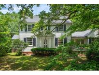 Charming white two-story home with black shutters surrounded by lush green foliage at 6 Sayle Rd, Charleston, SC 29407