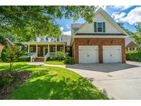 Charming brick home with a manicured lawn and a two-car garage on a sunny day at 8725 Herons Walk, North Charleston, SC 29420