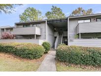 Exterior view of a well-maintained condo building with landscaped bushes and gray facade at 902 Greenmeadow Dr, Goose Creek, SC 29445