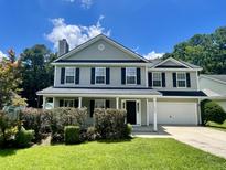 Charming two-story home with gray siding, black shutters, a green lawn, and a two car garage at 1039 Steelechase Ln, Hanahan, SC 29410