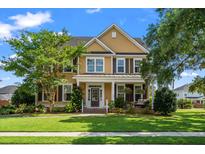 Charming two-story home featuring a covered front porch, a well-manicured lawn, and mature trees at 129 Saluda Dr, Moncks Corner, SC 29461