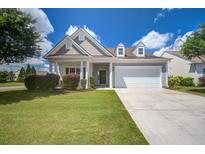 Charming one-story home showcasing manicured lawn, beautiful landscaping, and a two-car garage on a sunny day at 129 Schooner Bend Ave, Summerville, SC 29486