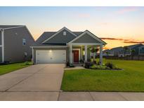 Charming single-Gathering home features a well-manicured lawn, covered porch, and an attached two-car garage at sunset at 160 Greenbelt Ct, Summerville, SC 29485