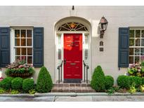 Inviting facade featuring a vibrant red door, complemented by classic architectural details and lush landscaping at 2 Bedons Aly, Charleston, SC 29401