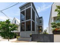 Charming two-story home with a screened porch, yellow door, and gray picket fence for added curb appeal at 211 Line St, Charleston, SC 29403