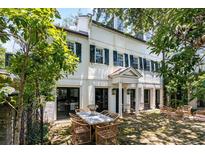 Elegant white home with black shutters featuring an inviting outdoor patio with dining and seating areas at 22 Lamboll St # C, Charleston, SC 29401
