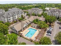 A picturesque aerial view of a community pool and apartment complex surrounded by lush greenery at 2244 Ashley Crossing Dr # 1125, Charleston, SC 29414