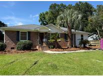 Charming brick home with a well-manicured lawn and mature landscaping, including palm trees at 2456 Lantern St, Charleston, SC 29414