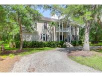 Charming two-story home with a gravel drive, lush landscaping, and a welcoming front porch at 2494 Cape Rd, Johns Island, SC 29455