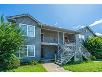 Well-maintained two-story condo building with gray siding, metal stairs, and green lawn under a clear blue sky at 2601 Riverridge Ct # A, Moncks Corner, SC 29461