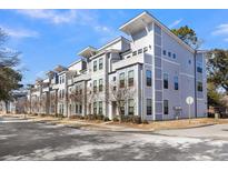 Modern townhome exterior showcasing contemporary architecture, gray siding, and a well-maintained street view under a clear blue sky at 4587 Summey St, North Charleston, SC 29405