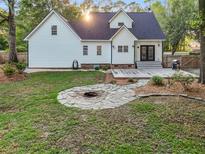 Inviting backyard with stone fire pit, deck, and well-maintained lawn, perfect for outdoor entertaining and relaxation at 1260 Old Whitesville Rd, Moncks Corner, SC 29461