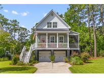 Charming two-story home featuring a welcoming front porch, two-car garage, and lush landscaping at 129 Martins Point Dr, Wando, SC 29492
