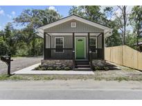 Charming home featuring a covered front porch with a bright green door and manicured landscaping at 227 Grace St, Walterboro, SC 29488