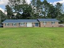 Charming brick home featuring a well-manicured lawn and complemented by mature trees at 306 Park St, Saint George, SC 29477