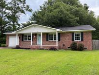 Charming one-story red brick home with a well-manicured lawn, a light blue door and black shutters at 352 Oxford Rd, Ladson, SC 29456