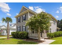 Charming two-story home featuring gray siding, black shutters, a welcoming porch, and lovely landscaping with a mature tree at 4140 Home Town Ln, Ravenel, SC 29470