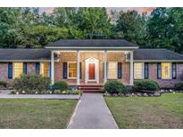 Charming brick home with a inviting red door, manicured landscaping, and classic shutters at 598 Maple Branch Rd, Reevesville, SC 29471
