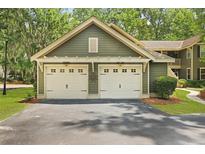 Attached two-car garage with white doors complements the green exterior and lush landscaping of this lovely home at 8400 Camp Gregg Ln, North Charleston, SC 29418