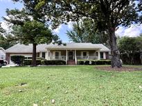 Charming one-story home with inviting front porch and mature trees on a well-manicured lawn at 14 Ashland Dr, Charleston, SC 29407