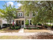 Charming two-story home featuring a quaint front porch, complemented by lush landscaping and inviting curb appeal at 165 Village Ponds Dr, Summerville, SC 29483