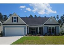 Charming one-story home with blue siding, a two-car garage, and a well-manicured front lawn at 265 Huguenot Trl, Huger, SC 29450