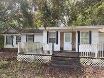 Exterior front view of a single-story home featuring white siding, and a small porch with lattice trim at 301 Haynesville Rd, Moncks Corner, SC 29461