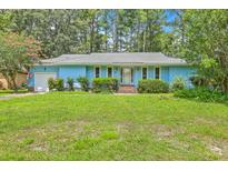 Charming blue home featuring a well-manicured lawn and attached garage in a lush green neighborhood at 312 Woodward Blvd, Summerville, SC 29483