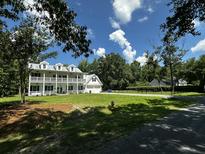 Charming two-story home with a white facade, multiple balconies, a spacious green lawn, and a two-car garage at 5681 Captain Kidd Rd, Hollywood, SC 29449