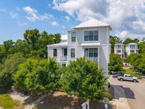 Stylish three-story home featuring a white metal roof and beautifully landscaped surroundings with mature trees at 992 Key Colony Ct, Mount Pleasant, SC 29464