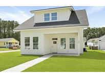 Charming white two-story home with covered porch and well-manicured lawn at 104 Brightwood Dr, Huger, SC 29450