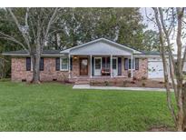 Charming brick home featuring a well-manicured lawn, covered porch, and updated front door at 104 Jackson Rd, Ladson, SC 29456