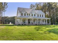 Stunning two-story home with a sprawling porch, lush lawn, and mature trees, offering curb appeal and outdoor space at 1130 Plantation Overlook Dr, Moncks Corner, SC 29461