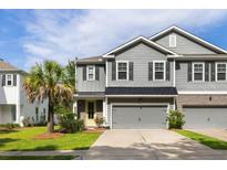 Charming two-story home featuring a gray exterior, well-manicured lawn, and a delightful yellow front door at 1682 Mermentau St, Mount Pleasant, SC 29466