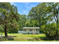Charming single-story home with a lush green lawn and mature trees, creating a serene and inviting curb appeal at 1879 Richmond St, Charleston, SC 29407