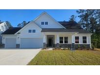 Beautiful two-story home with white siding, stone accents, and a well-manicured lawn in a peaceful community at 230 Huguenot Trl, Huger, SC 29450