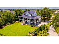 Beautiful two-story home with lush green lawn, screened in porches, and large wooden staircase at 2312 Rushland Landing Rd, Johns Island, SC 29455