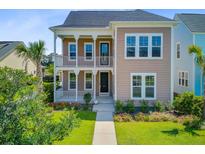 Charming tan two-story home featuring a double porch, manicured lawn, and lush landscaping at 357 Parish Farms Dr, Summerville, SC 29486