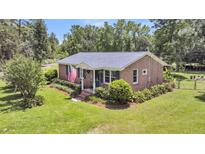 Charming brick home with well-maintained lawn, pretty shrubbery, and an American flag waving at 7274 Commodore Rd, Hollywood, SC 29449