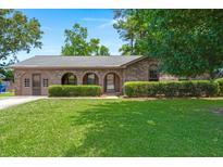 Charming single-story brick home with arched entryway, lush green lawn, and well-maintained landscaping at 8116 Long Shadow Ln, North Charleston, SC 29406