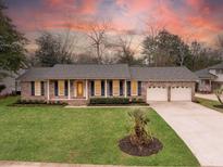 Brick house with a well-manicured lawn, mature trees, and a two-car garage, providing excellent curb appeal at 1043 Dominion Dr, Hanahan, SC 29410