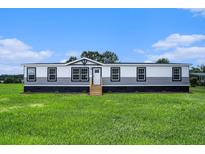 Charming manufactured home showcasing a well-manicured lawn and classic architectural details at 1326 Givhans Rd, Ridgeville, SC 29472