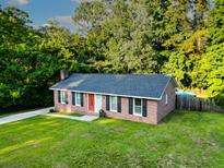 Brick house with a well-manicured lawn, a red front door, and a backdrop of lush trees at 214 E Edgefield Dr, Summerville, SC 29483