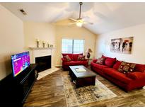 Inviting living room with a fireplace, ceiling fan, and comfortable red couches for a cozy gathering space at 2186 Spoleto Ln, North Charleston, SC 29406