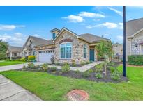 Charming single-story home with a stone facade, well-manicured lawn, and an attached two car garage at 269 Village Stone Cir, Summerville, SC 29483