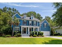 Charming blue two-story home featuring a well-manicured lawn, a columned porch and an attached two-car garage at 3574 Toomer Kiln Cir, Mount Pleasant, SC 29466