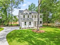 Inviting two-story white home with a manicured lawn and a curving driveway leading up to the house at 5710 Barbary Coast Rd, Hollywood, SC 29449