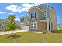 Charming two-story home featuring stone accents, a two-car garage, and a well-maintained lawn at 644 Red Monarch Way, Moncks Corner, SC 29461