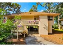 Inviting condo exterior decorated with patriotic bunting and flags, featuring a charming entryway and well-maintained landscaping at 837 Club Cottage Rd, Edisto Island, SC 29438