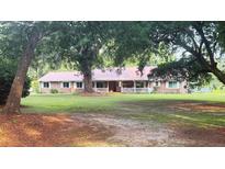 Charming single-story brick home with a metal roof, inviting front porch, and mature trees in a spacious yard at 138 Brant Acres Ln, Bonneau, SC 29431